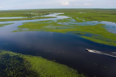 Gün batımında sürat teknesiyle nehrin üzerinde çekilmiş bir fotoğraf. Nehirde hareket eden bir teknenin kuş bakışı görüntüsü.