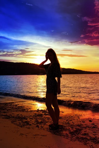 Silhueta da mulher contra um pôr-do-sol no oceano — Fotografia de Stock