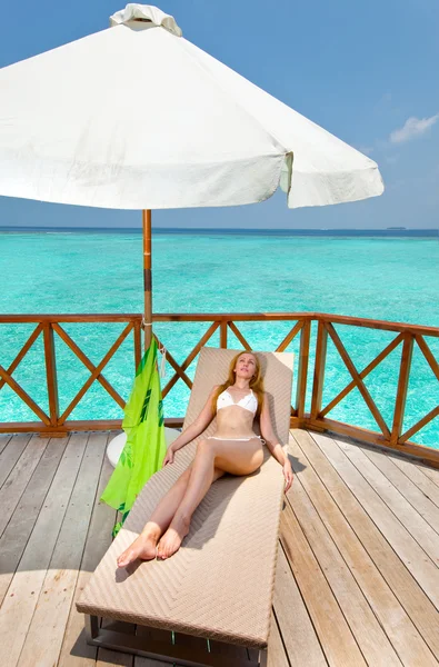 Mujer joven broncea en una terraza de villa de agua en el océano Maldivas —  Fotos de Stock