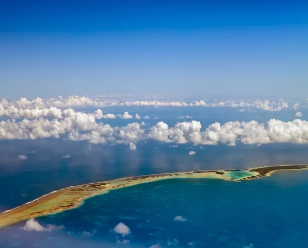 Polynésie. atol ring v oceánu je viditelný skrz mraky. Letecký pohled. — Stock fotografie