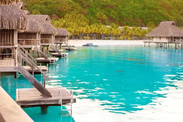 Tipikus polinéziai táj - tengerpart pálmafákkal és kis vízparti házakkal — Stock Fotó