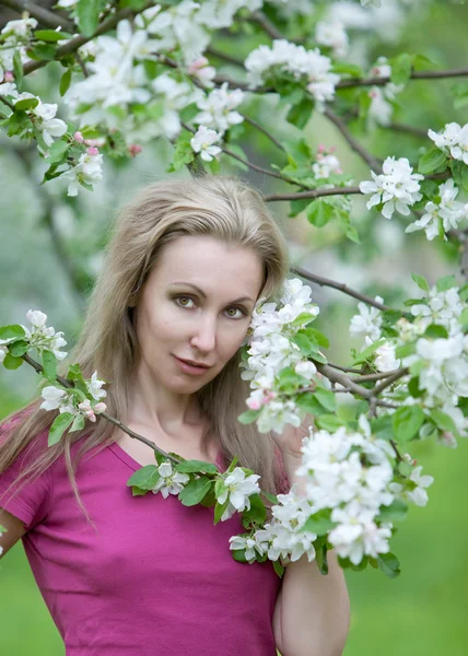 Jovem mulher atraente em pé perto da macieira florescente . — Fotografia de Stock