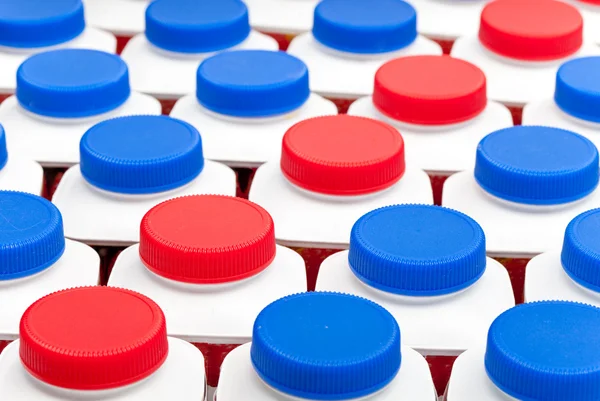 Количество бутылок йогурта с темно-синими и красными крышками — стоковое фото