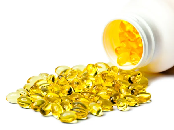 Yellow liquid capsules lie near a bottle — Stock Photo, Image