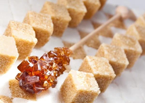 Kostki cukru brązowego cukru i cukierki nie rafinowany trzcina leżą na kawałki cukru białego — Zdjęcie stockowe