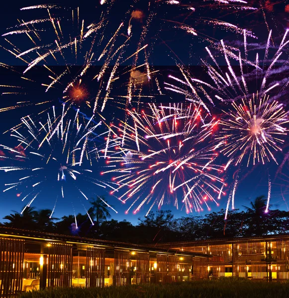 Fogos de artifício festivos sobre casas em fogos e silhuetas de palmeiras — Fotografia de Stock