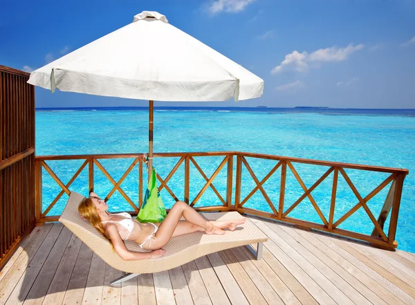 Young woman tans on a water villa terrace , Maldives — Stock Photo, Image