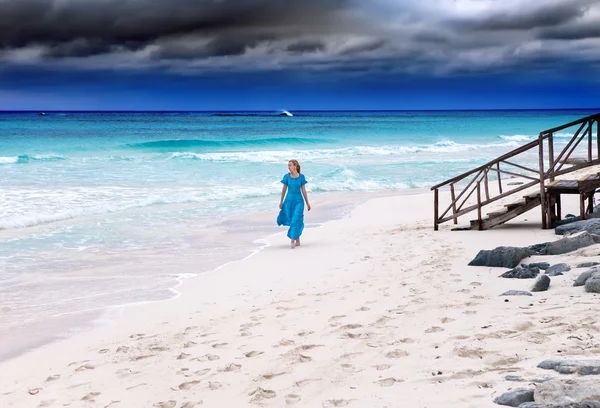 De vrouw in een lange blauwe jurk gaat aan de stormachtige Zeekust — Stockfoto