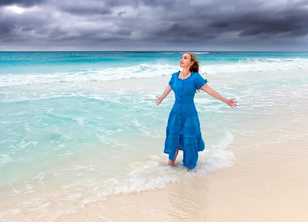 De vrouw in een lange blauwe jurk in een branding van stormachtige zee — Stockfoto