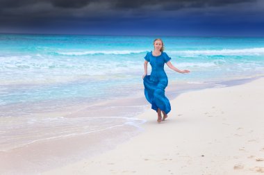 fırtınalı denizde sörf içinde koşmak uzun mavi elbiseli kadına