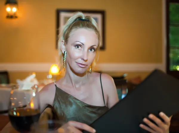 The beautiful young woman at restaurant holds the menu