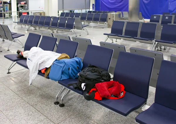 Passagier schläft nach Flugausfall auf Sitzen in leerem Nachtflughafen — Stockfoto