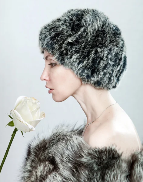Mladá krásná žena v srsti a s bílou růží — Stock fotografie