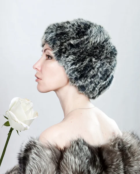 La giovane bella donna in pelliccia e con una rosa bianca — Foto Stock