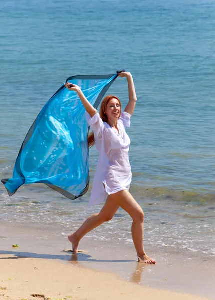 Молодая привлекательная женщина на берегу моря с голубым шарфом в руках — стоковое фото