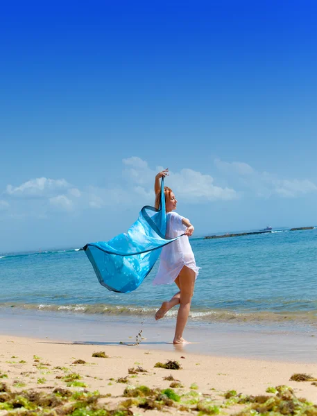 The young attractive woman jumping with a blue scarf in hands — Stock Photo, Image