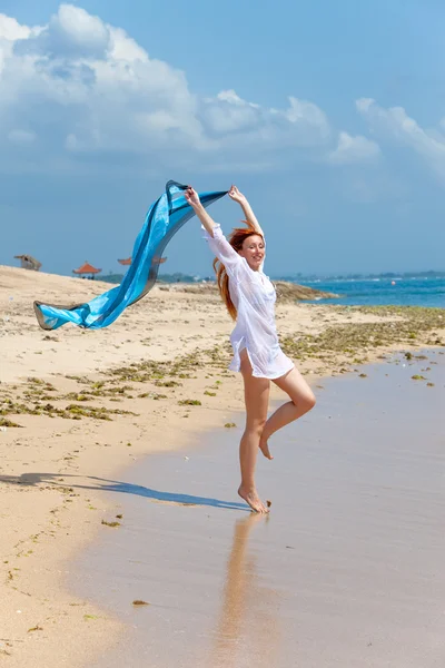 Молодая привлекательная женщина на пляже с голубым шарфом в руках — стоковое фото