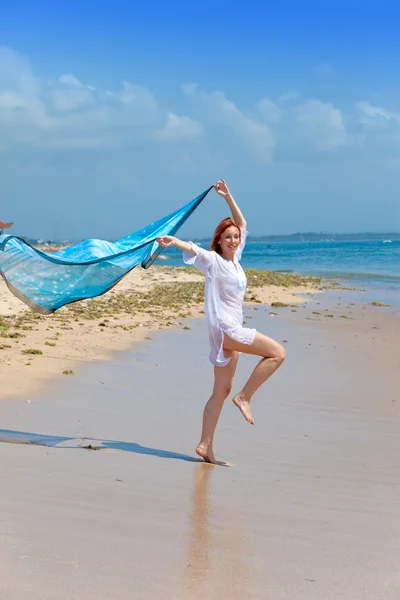 The young attractive woman on a beach with a blue scarf in hands — Stock Photo, Image