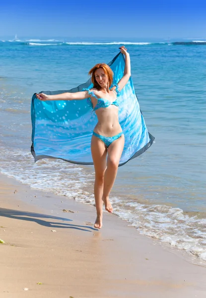 Młoda atrakcyjna kobieta na plaży z niebieski szalik w ręce — Zdjęcie stockowe