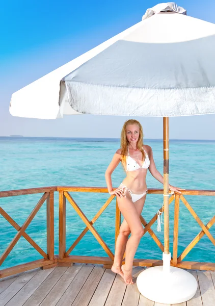 Jonge vrouw tans op een terras van water villa, Maldiven — Stockfoto