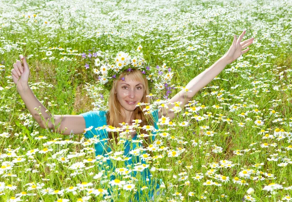 Gelukkig jonge vrouw in een krans van wilde bloemen op het gebied van kamille — Stockfoto