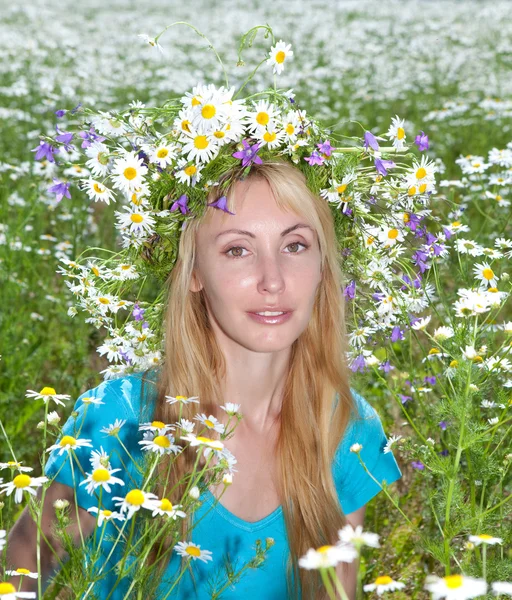 Glückliche junge Frau im Kranz aus Wildblumen im Kamillenfeld — Stockfoto