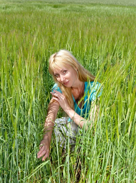 Die glückliche junge Frau auf dem Feld des grünen Ohres — Stockfoto
