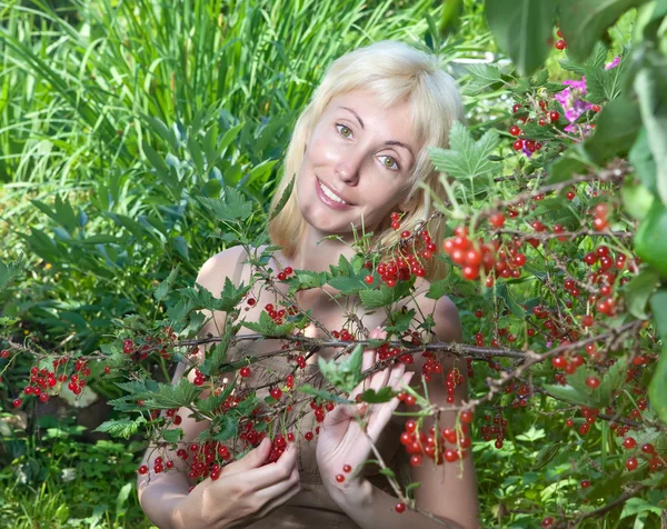 La jeune belle fille près d'un buisson de groseille rouge — Photo