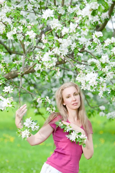 Giovane donna attraente in piedi vicino al melo in fiore — Foto Stock