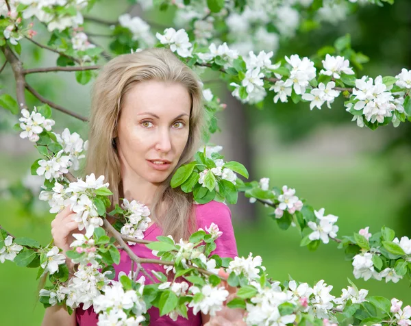 Ung attraktiv kvinna står nära det blommande äppelträdet — Stockfoto