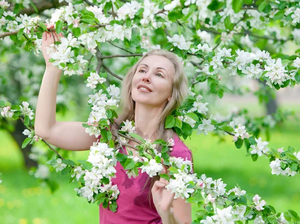 Mujer atractiva joven de pie cerca del manzano en flor —  Fotos de Stock
