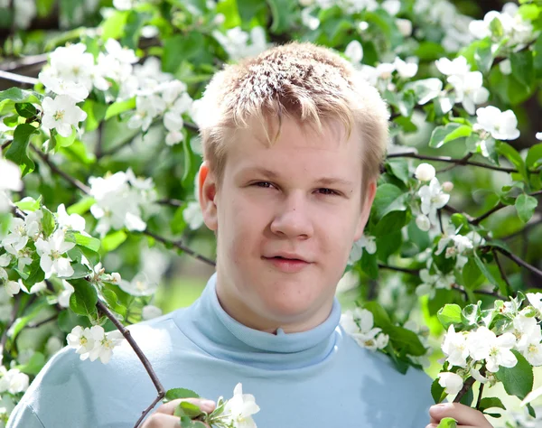 Молодой человек, подросток, стоящий рядом с цветущей яблоней . — стоковое фото