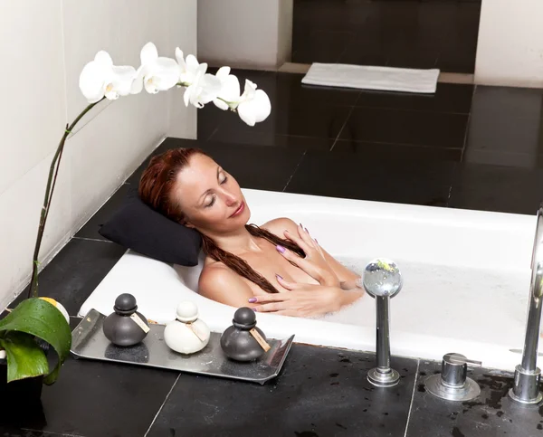 Woman lays in soapsuds in bathing, full water — Stock Photo, Image