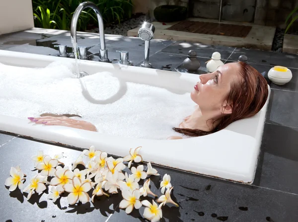 Mulher coloca em sabonetes em banho, água cheia — Fotografia de Stock