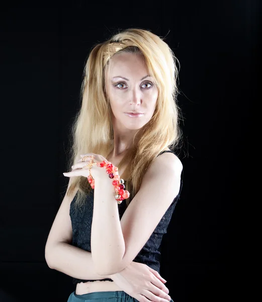 Beautiful young woman with long blonde hair and a red bracelet on a dark backgroun — Stock Photo, Image