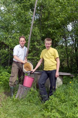 Çocuğun babası bir de bir kova su dökmek için yardımcı olur.