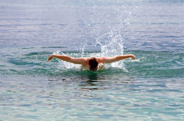 genç sporcu deniz yunus stilinde yüzüyor.