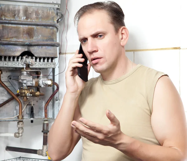 Mannen samtal per telefon att orsaka reparatör av gas varmvattenberedare — Stockfoto