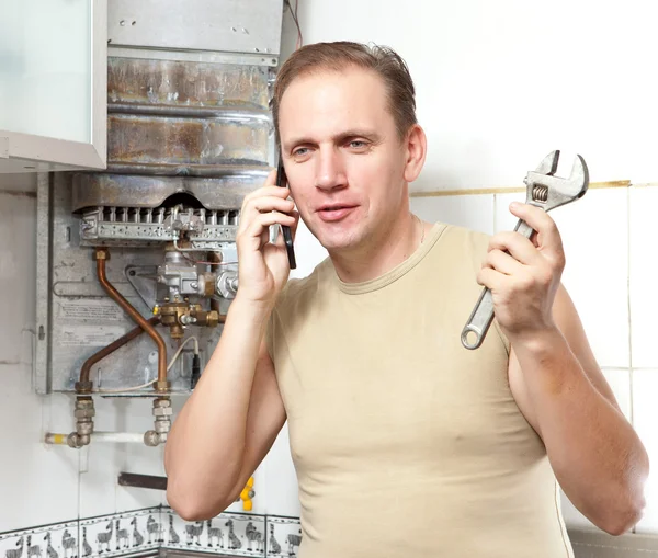 Mannen samtal per telefon att orsaka reparatör av gas varmvattenberedare — Stockfoto