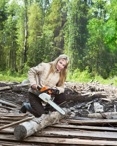 Den unga kvinnan i trä sågar ett träd en motorsåg — Stockfoto