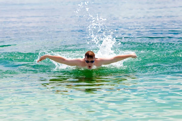 Sportieve jongeman zwemt in de zee dolfijn stijl. — Stockfoto