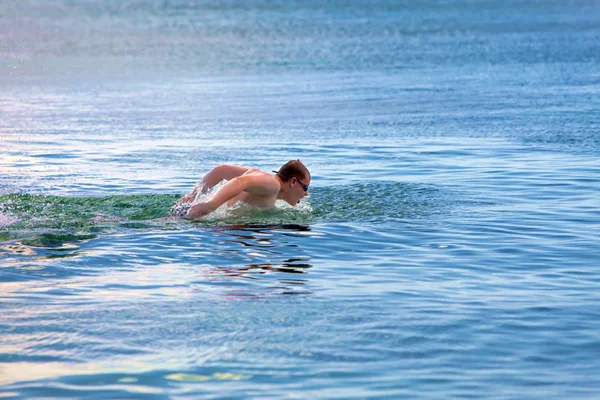 Sportieve jongeman zwemt in de zee dolfijn stijl. — Stockfoto
