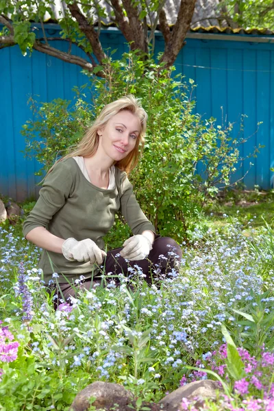 Jovem mulher bonita cuida atrás de plantas no jardim — Fotografia de Stock