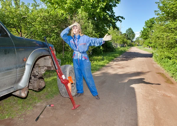 The woman in working overalls tries to replace a wheel at an off-road car — Stock Photo, Image