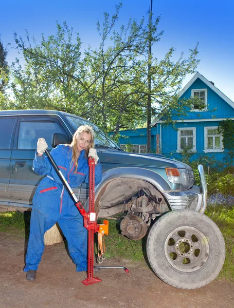 Kvinnan i arbetar overaller försöker byta ut ett hjul på en off-road bil — Stockfoto