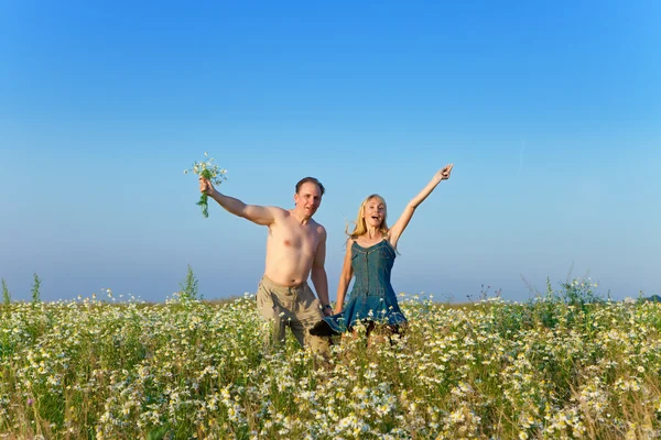 La feliz pareja joven en el campo de las manzanillas —  Fotos de Stock