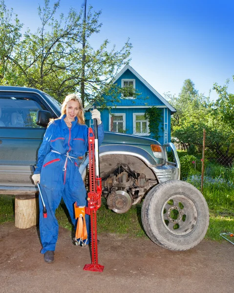 Kvinnan i arbetar overaller försöker byta ut ett hjul på en off-road bil — Stockfoto