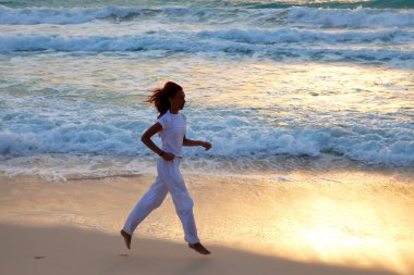 silueta de mujer, en la puesta del sol a lo largo de la costa del océano