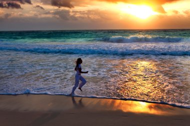 silueta de mujer, en la puesta del sol a lo largo de la costa del océano