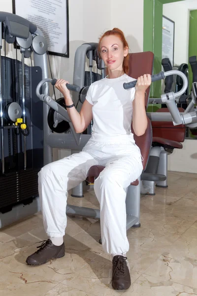 The young sporting woman in fitness center trains — Stock Photo, Image